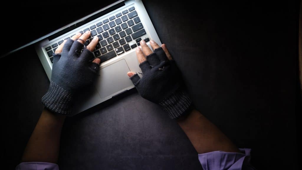 a person wearing gloves typing on a laptop